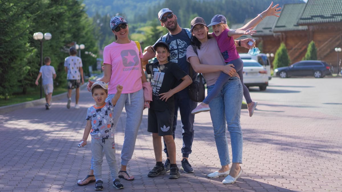 A joyful family of six spending quality time together in a scenic outdoor setting with mountains in the background.